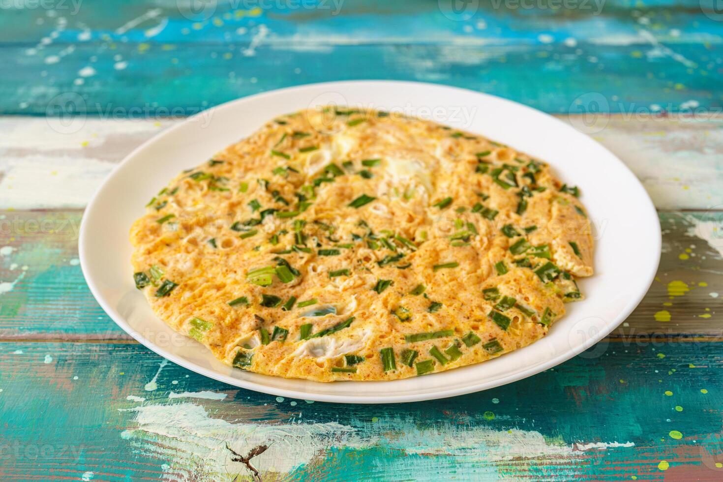 Fluffy omelet with fresh chives on a plate. Delicious egg dish for breakfast, brunch, or quick meal. Healthy and simple homemade food. photo