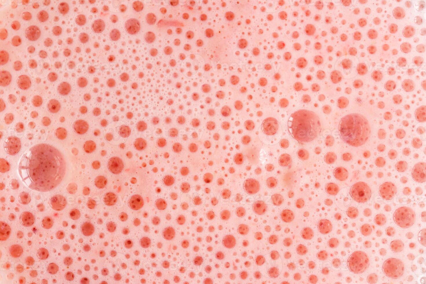 Pink foam texture with small bubbles on a light pink background. Close up macro view of liquid surface with air bubbles. Smooth beverage background abstract concept. photo