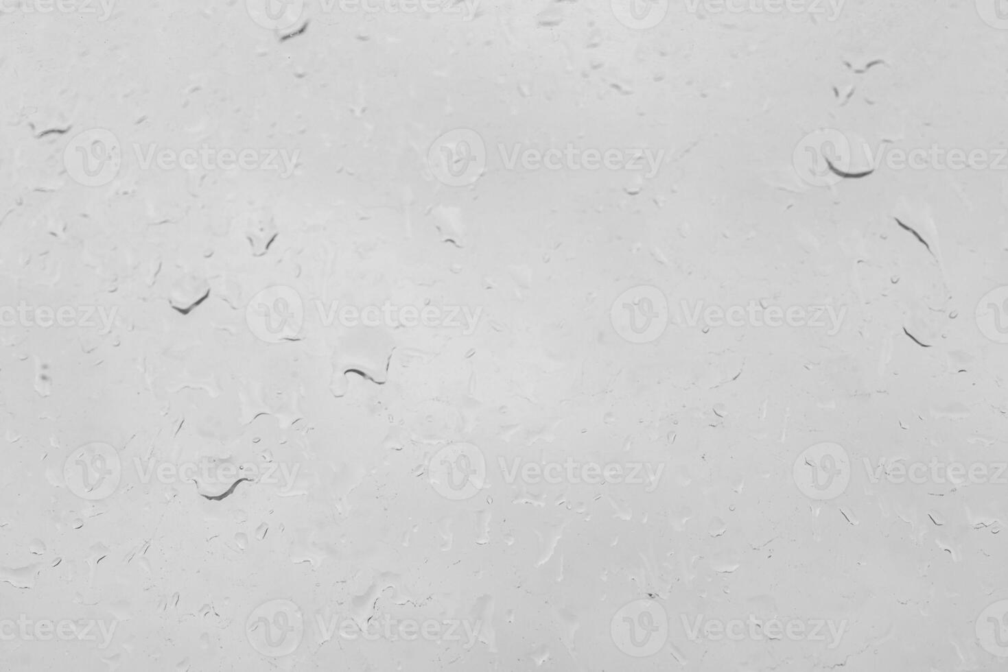 Rain drops on a window pane create a natural texture. Transparent liquid element for background or overlay effect concept on a gray surface. photo