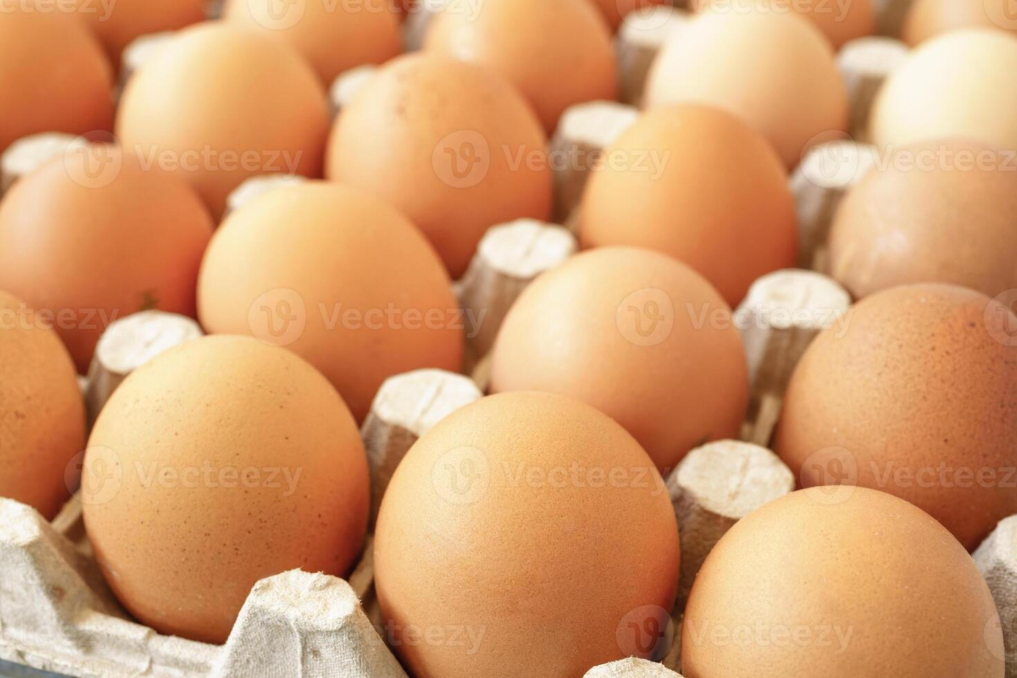 Brown chicken eggs in a cardboard tray on a wood background for farm and food concepts and healthy eating or cooking recipes and ingredients advertising. photo