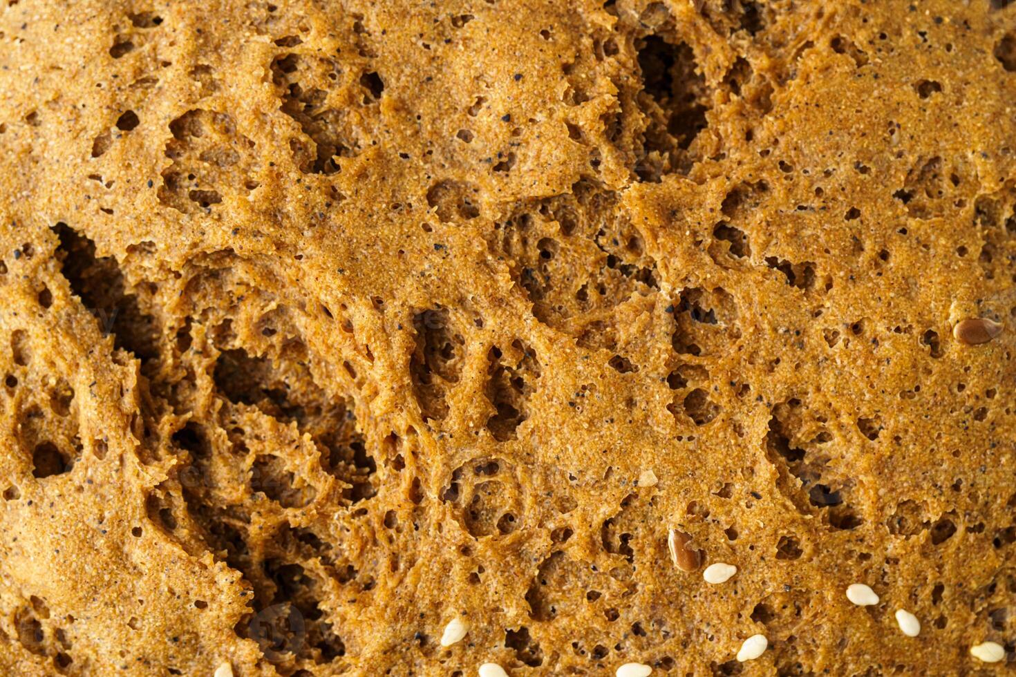 detailed macro view of wholesome whole grain bread texture showing the porous crust of rye country homemade bread, a baking sweet abstract background. photo