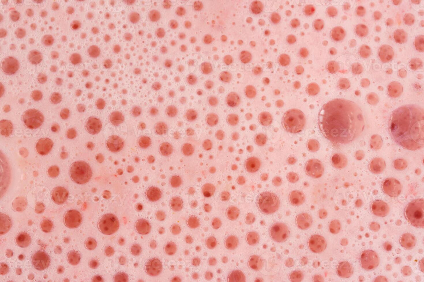 Macro shoot of pink foam texture with small bubbles on a light pink background. Close up macro view of liquid surface with air bubbles. Smooth beverage background abstract concept. photo
