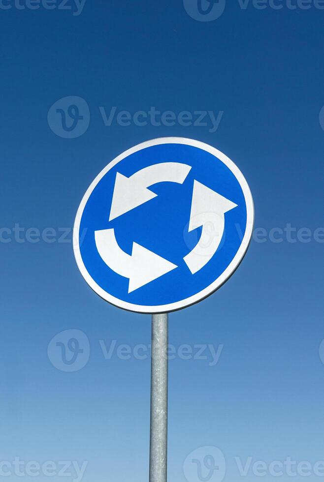 Roundabout crossroad road traffic sign against blue sky photo