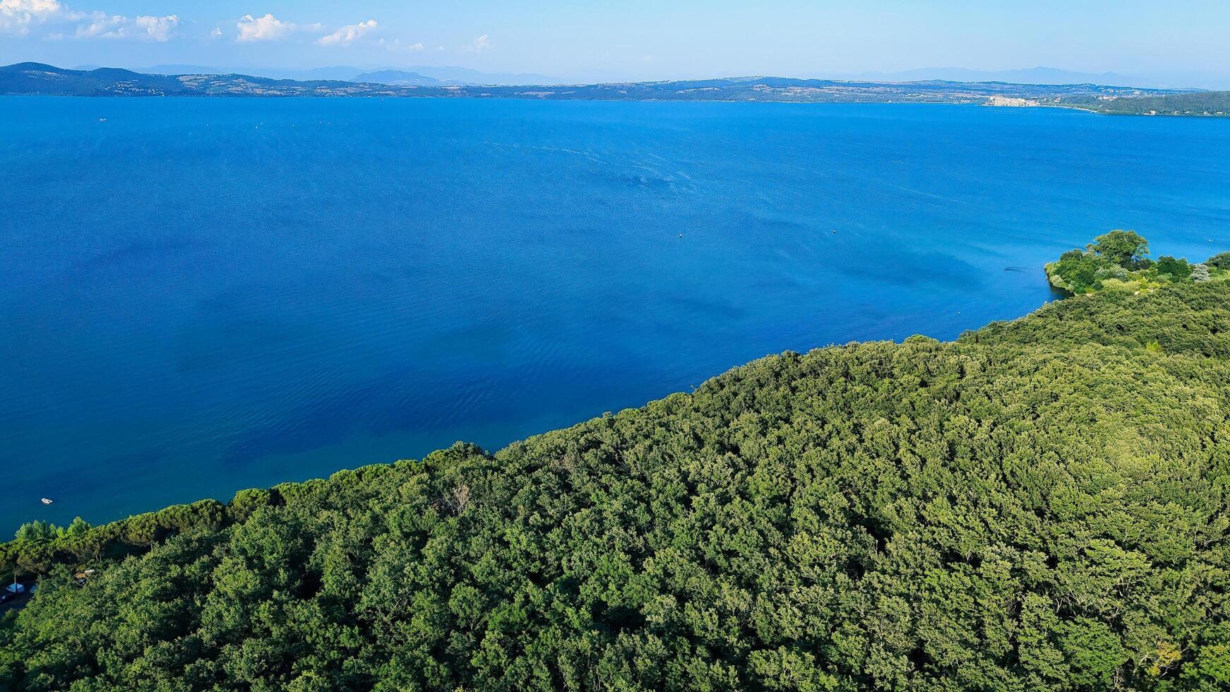 view of lake trasimeno with lush green forest covering its shoreline photo