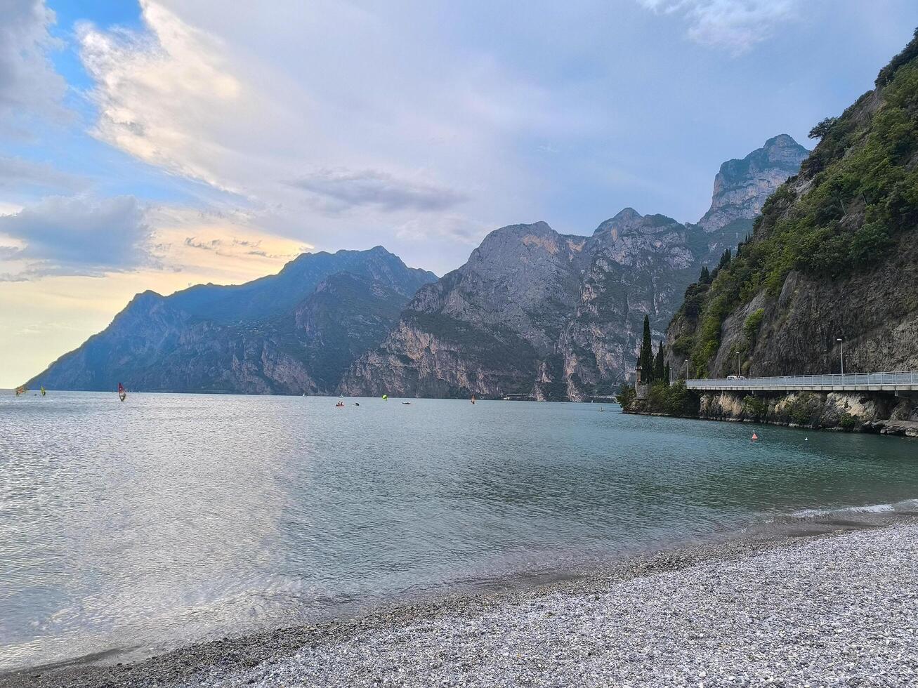 Soothing waters and majestic cliffs meet at the serene beach by Lake Garda at dusk photo