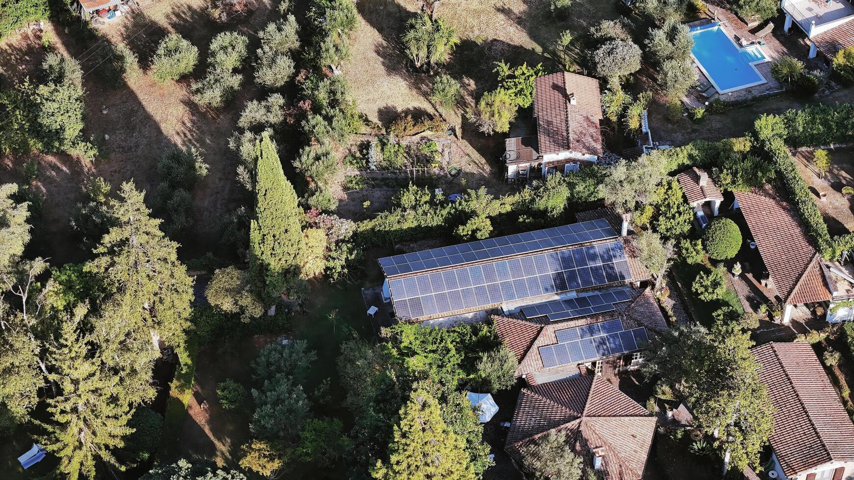 view of a charming countryside estate with solar panels surrounded by lush greenery and a refreshing pool under bright sunlight photo