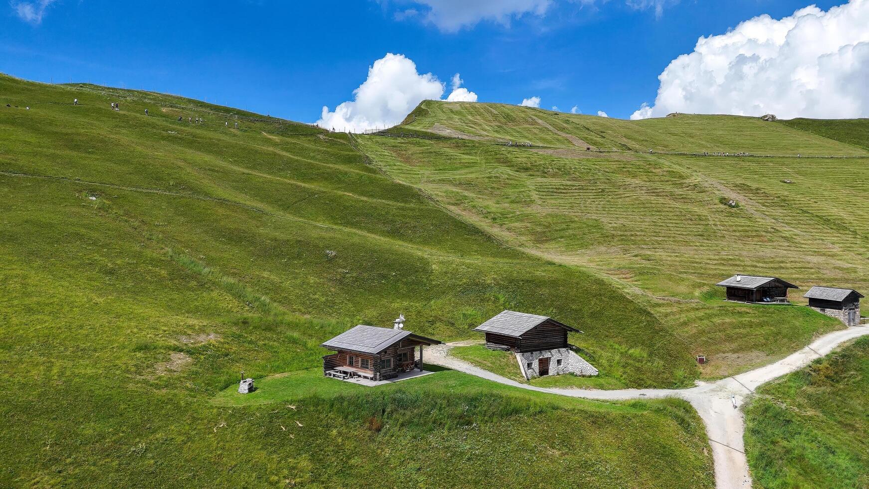 Breathtaking mountain landscape featuring rustic cabins nestled in vibrant green hills under a vivid blue sky on a sunny day photo