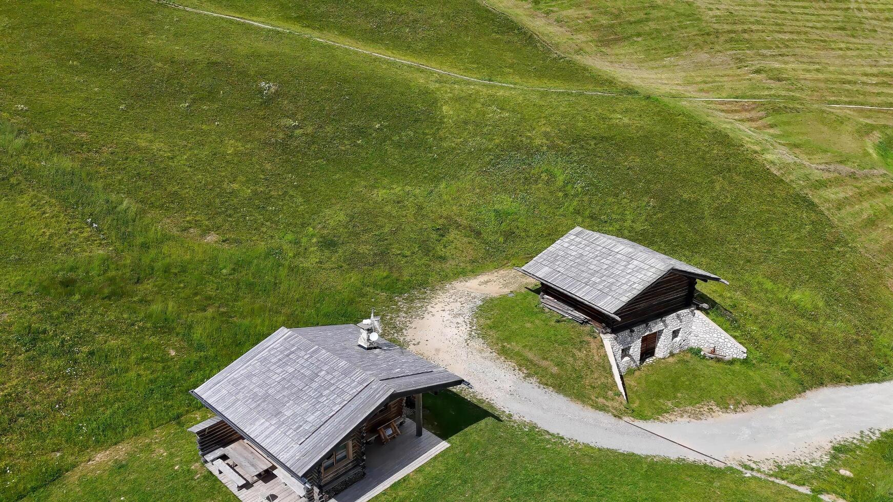 Rustic alpine cabins nestled in the grassy hills of a serene countryside during a bright summer day photo
