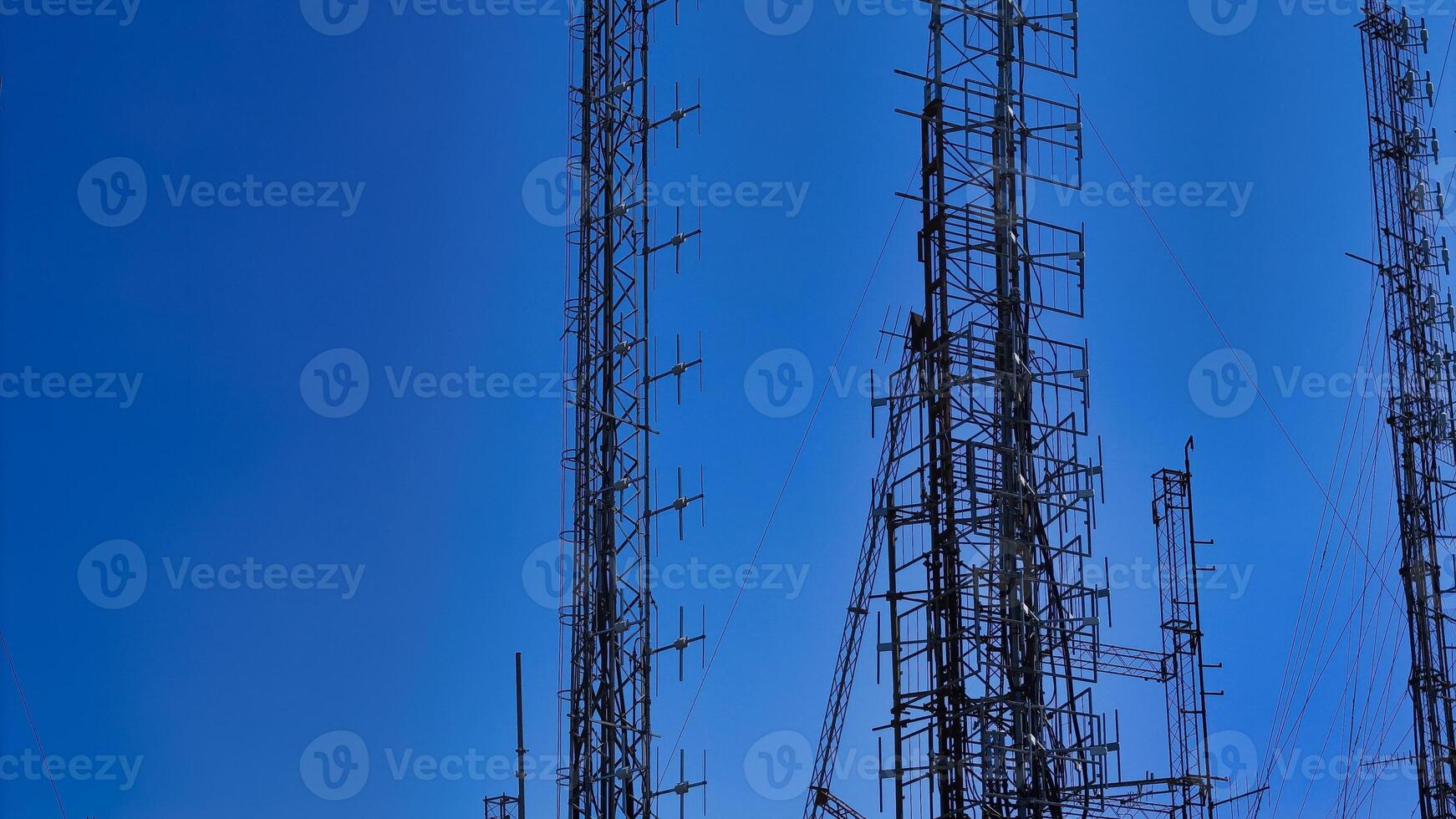 Tall communication towers against a bright blue sky, showcasing modern technology and network infrastructure photo