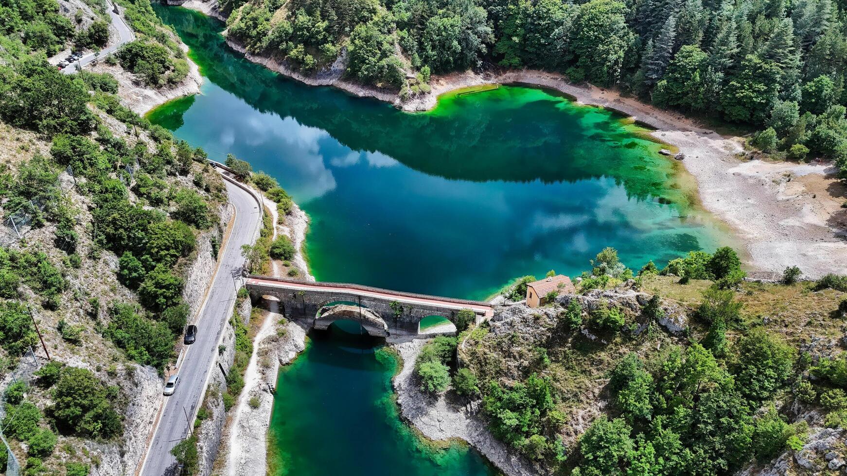 old bridge connecting two sides of a turquoise lake photo