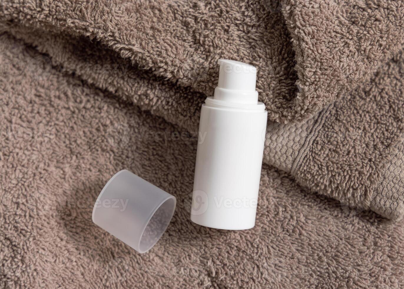 White cream pump bottle on brown folded towels top iew, cosmetic packaging mockup photo