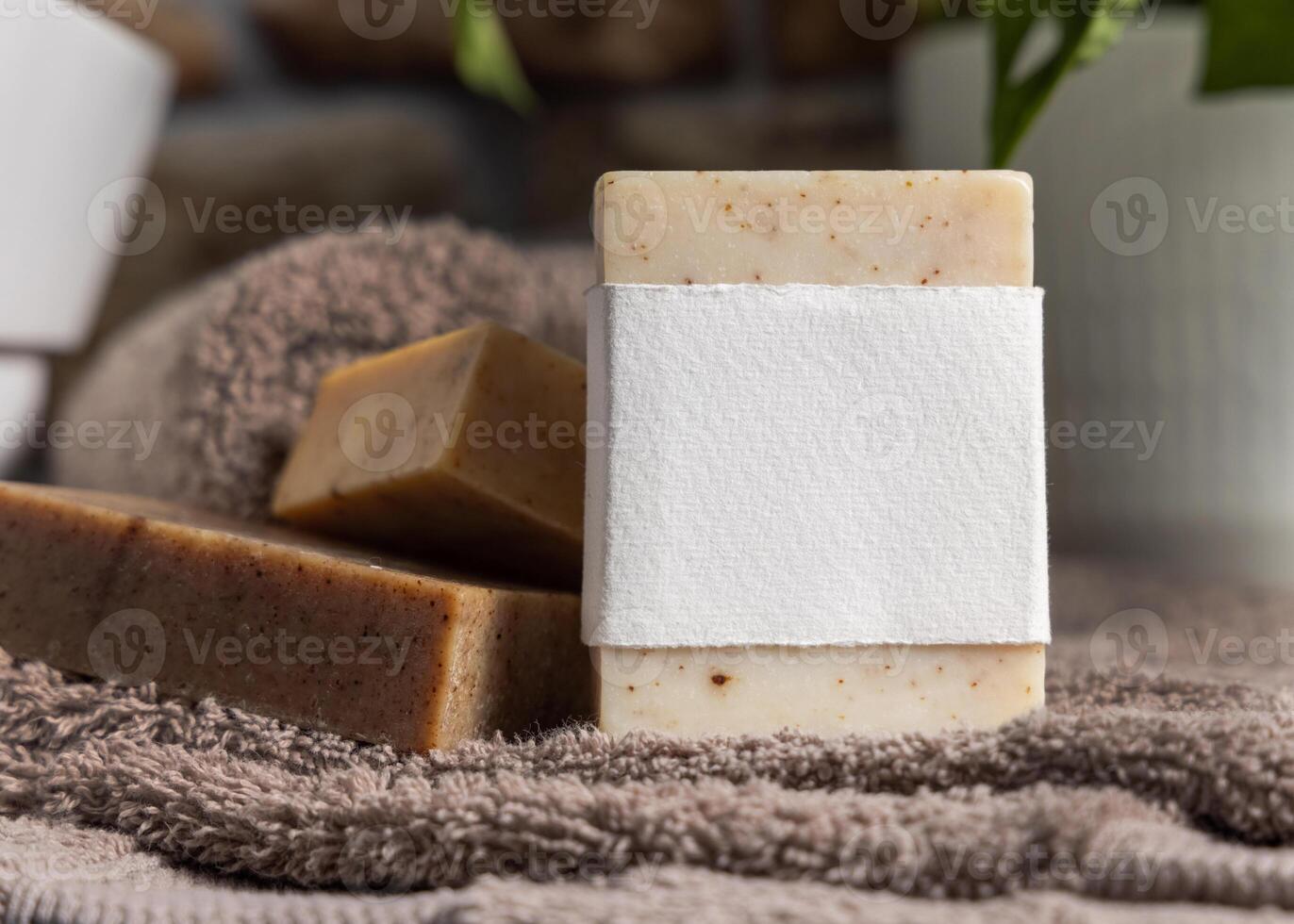Soap bar with blank label on brown towel near sink and plant in bathroom closeup, mockup photo