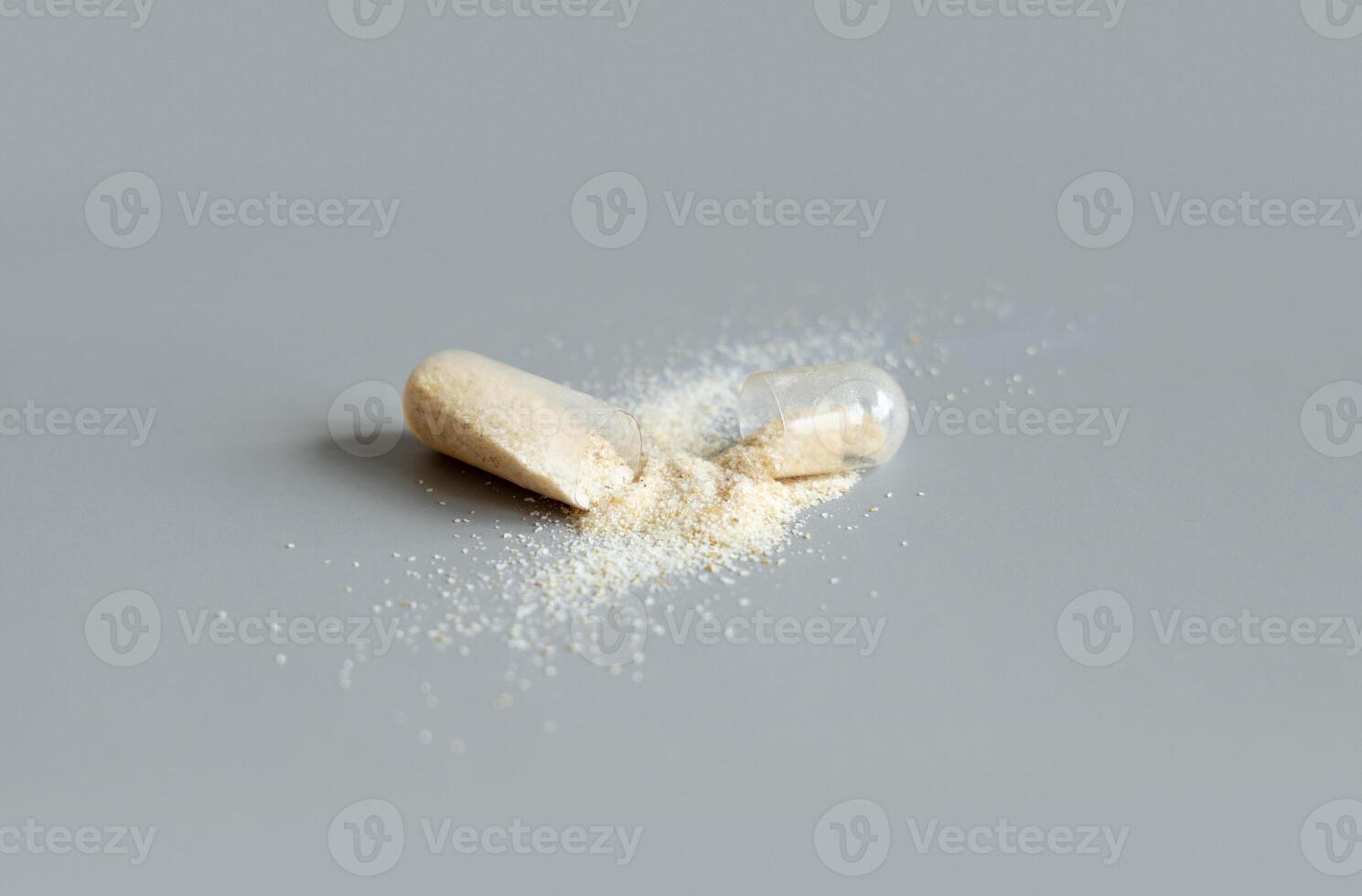 Opened Medical capsule to show beige powder on grey closeup. Dietary supplements photo