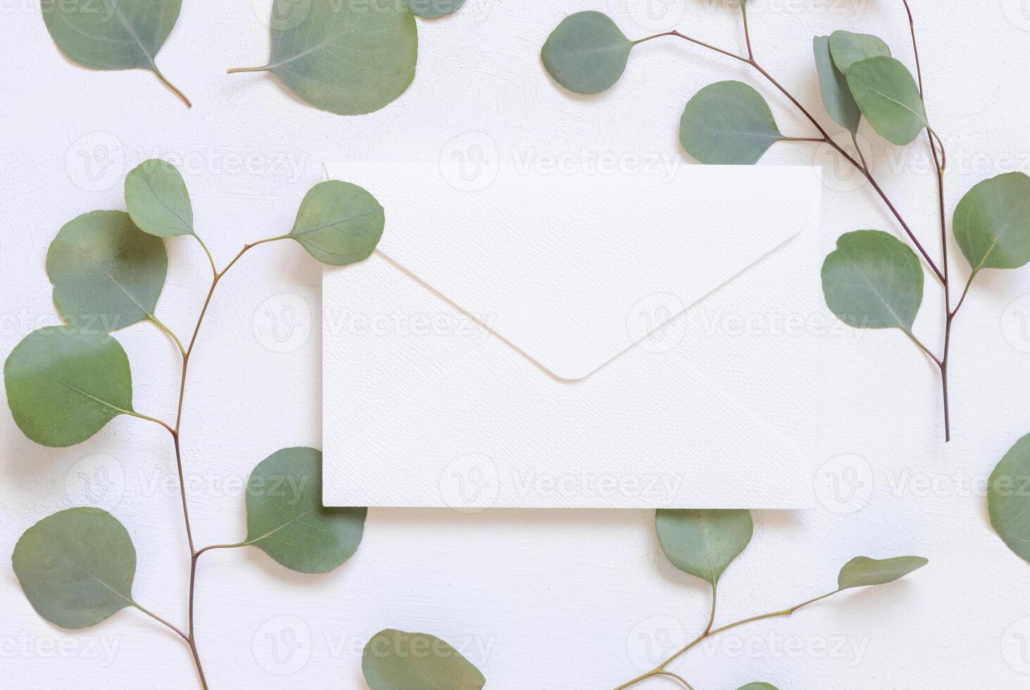 white Envelope on a table near green eucalyptus twigs and leaves, Wedding mockup photo