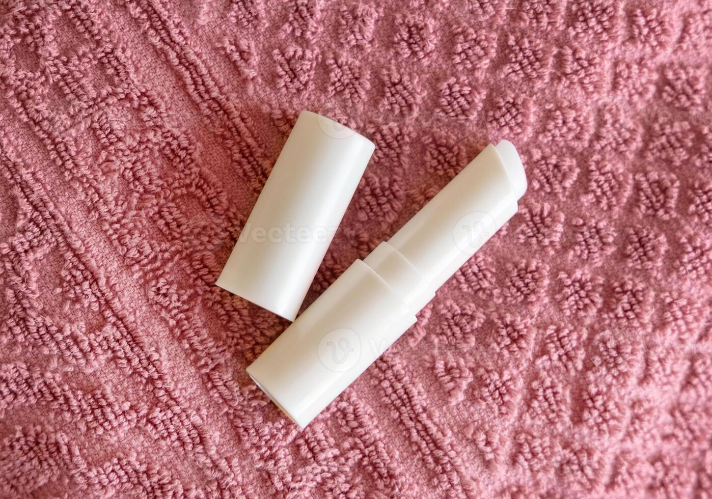 Opened lip balm stick on pink towels topview, lid mockup. Skincare beauty product photo