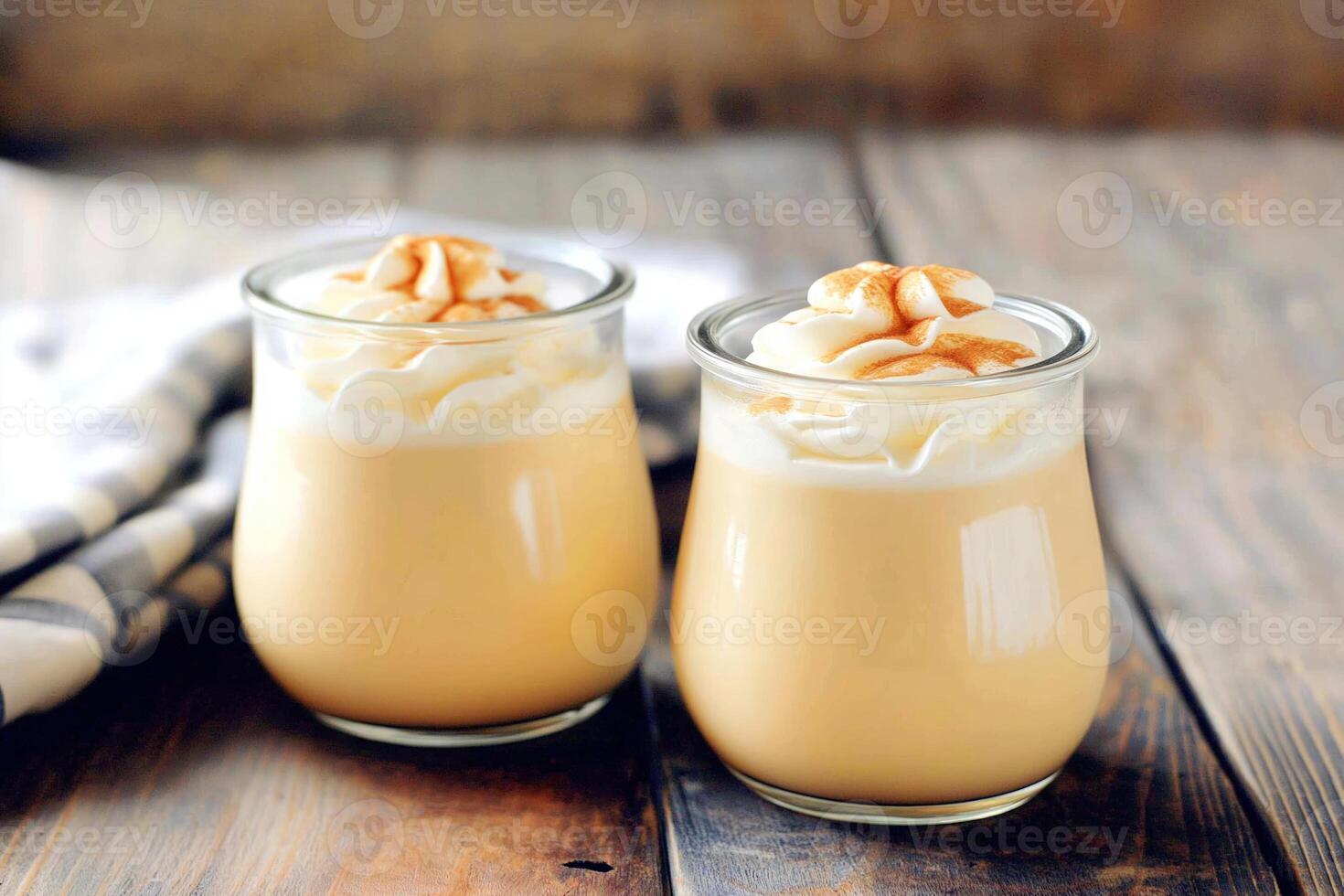 Two glass jars filled with creamy homemade caramel yogurt on old rustic wooden table photo