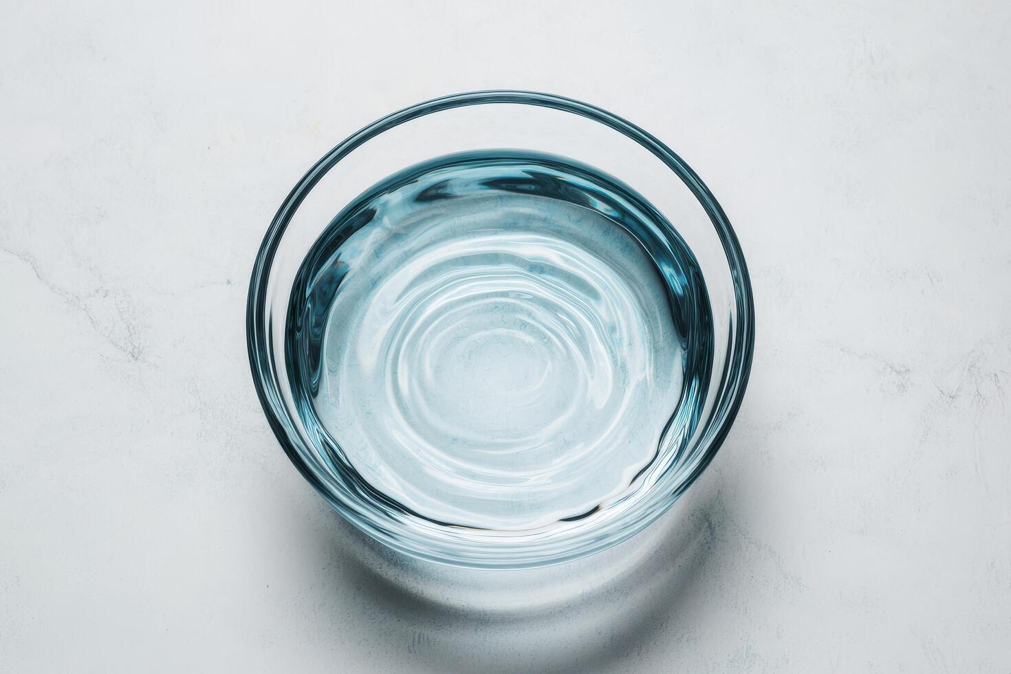 Clear glass bowl filled with water on a light background. Pure water unpolluted concept. photo