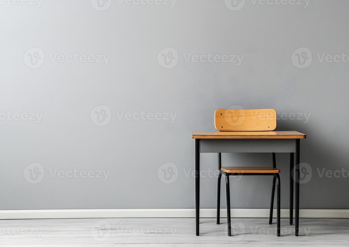 wide shot of empty school desk against smooth grey wall photo