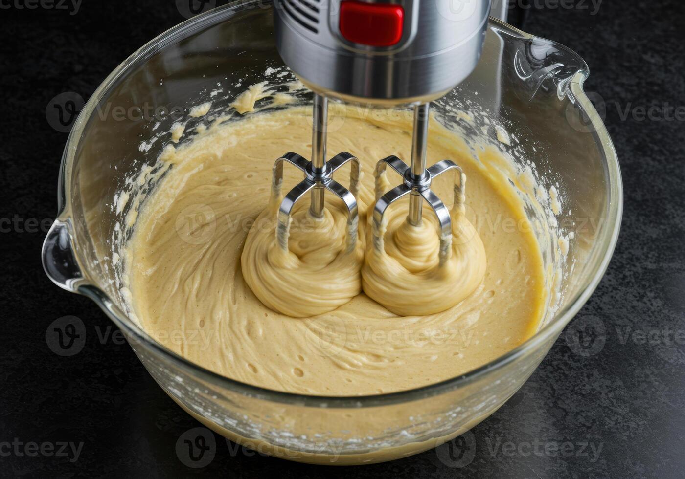 A glass bowl filled with batter being mixed with an electric hand mixer in a kitchen setting. photo