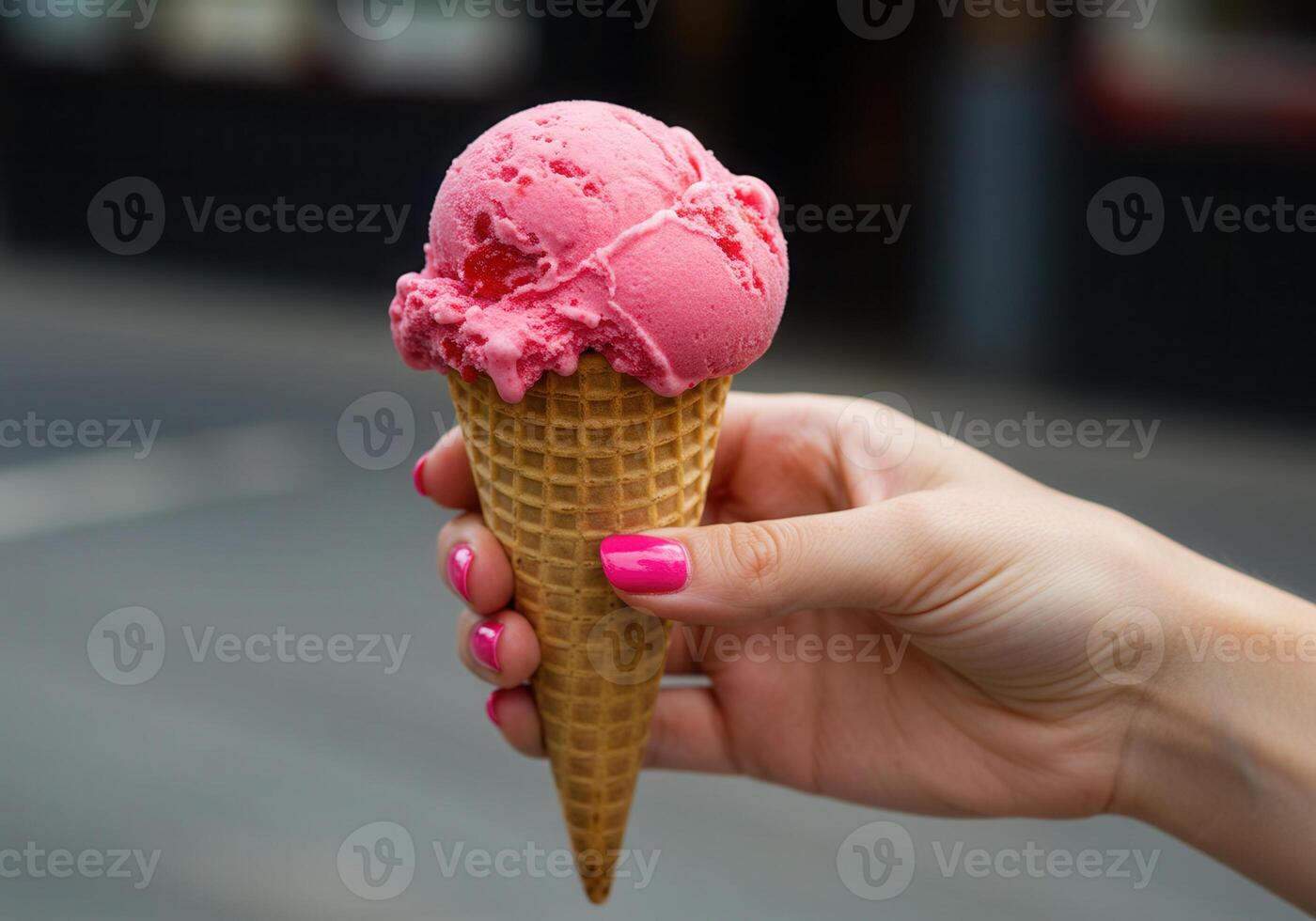 A refreshing strawberry ice cream cone is held, showing the delightful treat up close. photo