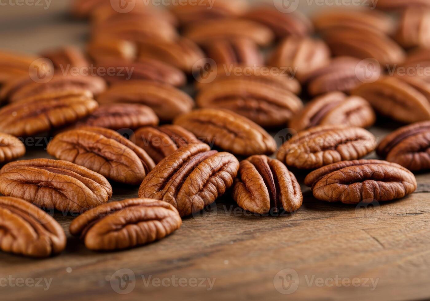 A collection of fresh, shelled pecan halves are displayed on a rustic wooden surface. photo