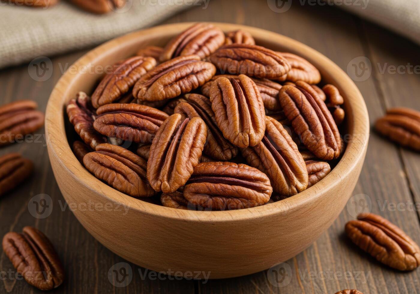 A wooden bowl filled with delicious shelled pecans on a wooden table. photo