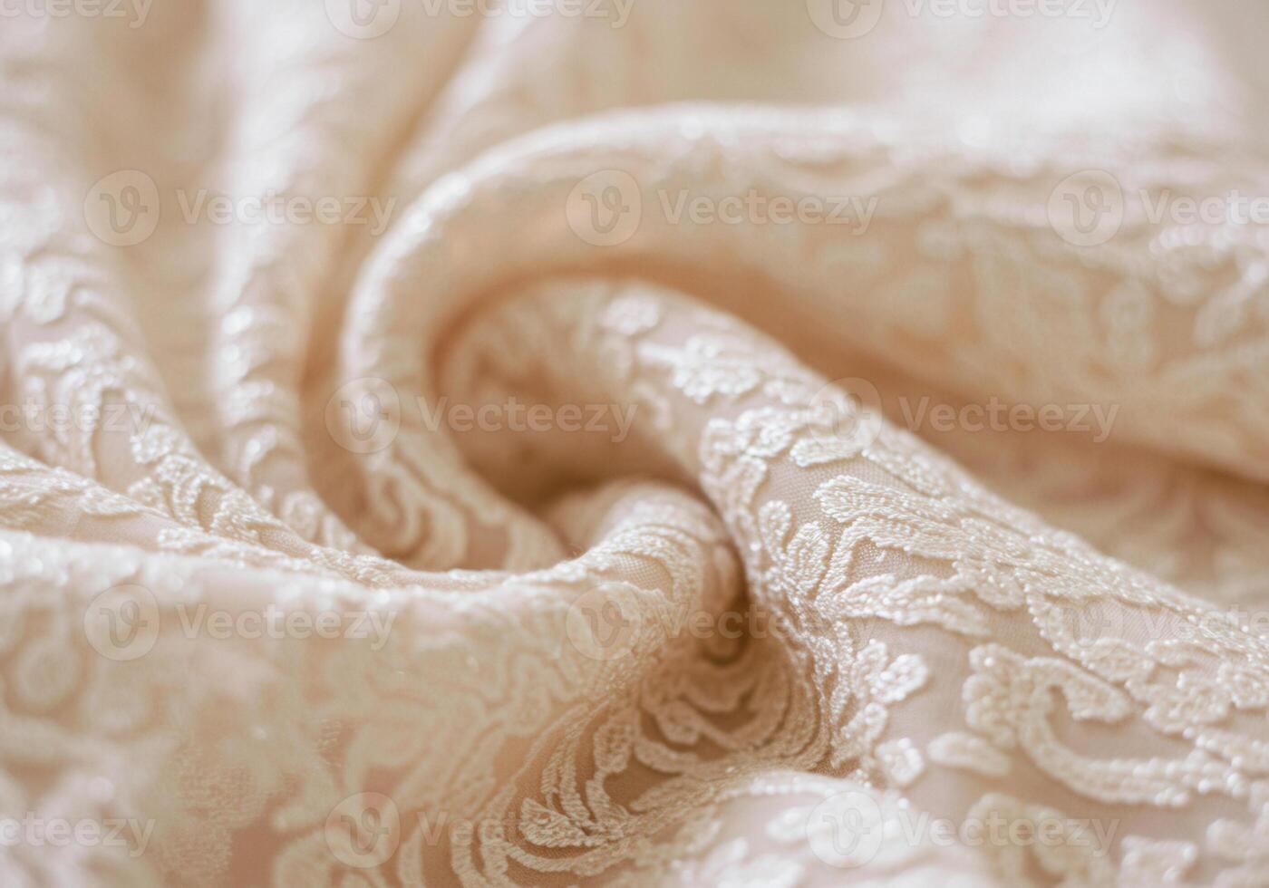 Elegant ivory lace fabric beautifully draped and softly lit creating an intricate texture. photo