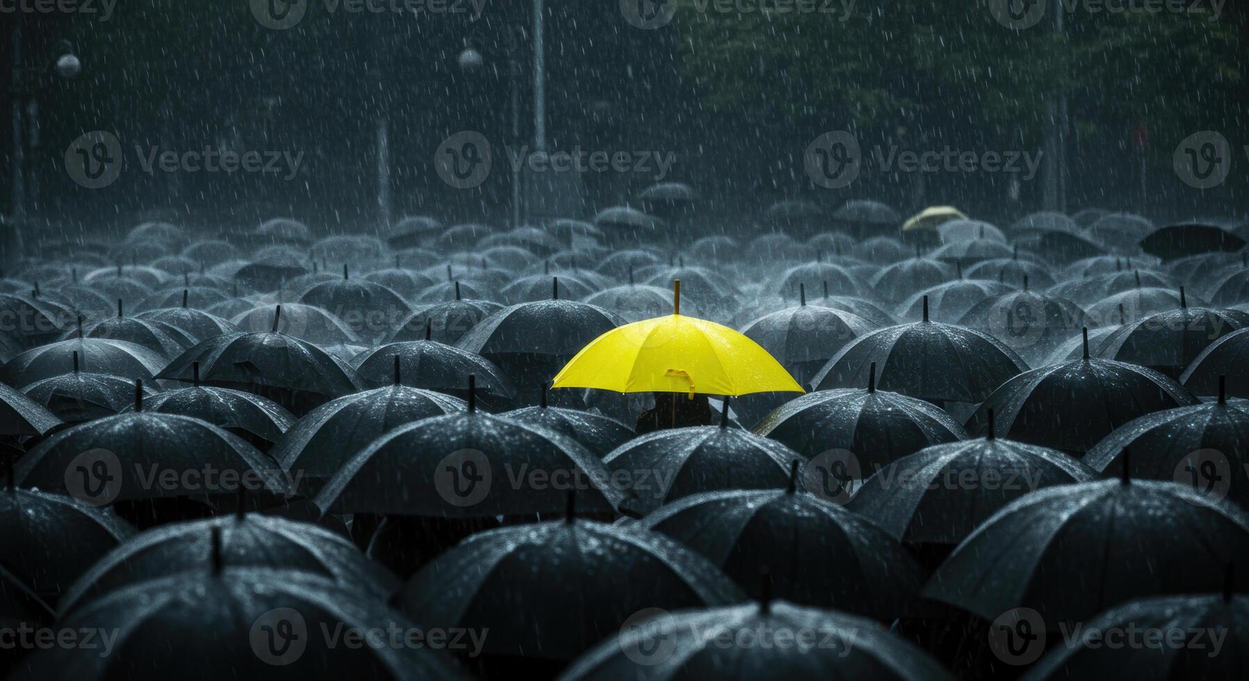 A yellow umbrella stands out in a crowd of black umbrellas under heavy rain. photo