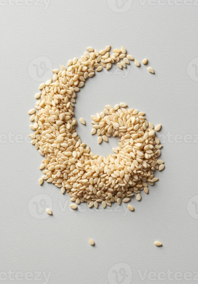 Sesame seeds arranged in a swirl on a light gray surface. photo