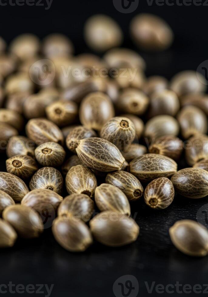 A collection of cannabis seeds resting on a dark surface, ready for planting. photo