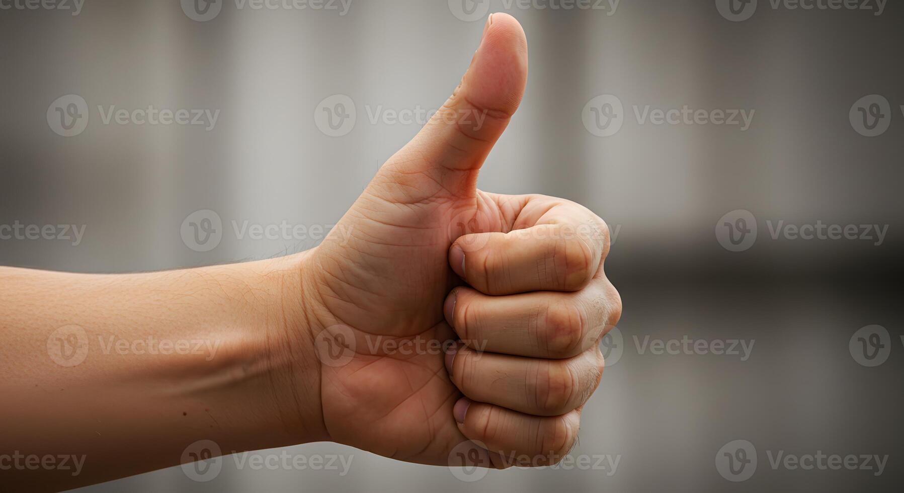 Hand giving a thumbs up gesture indicating approval or positivity in a soft-focused background photo