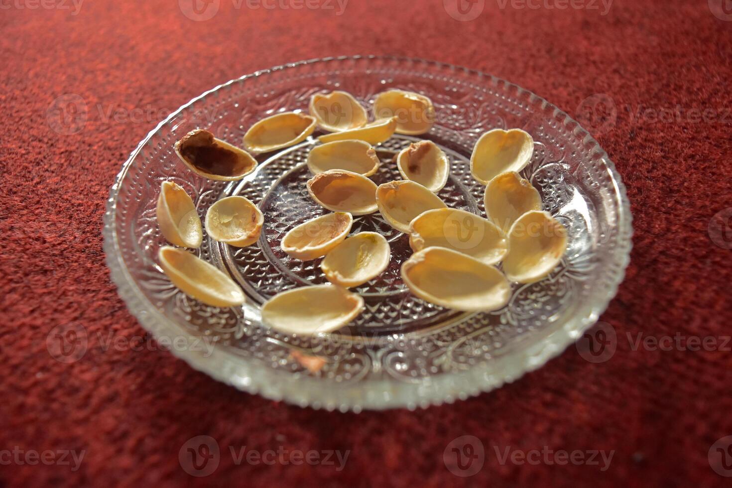 Close up of Pistachio nut shells or Pistacia vera on a clear saurcer, a cashew-related seed that can be eaten fresh or roasted and is commonly used in a variety of desserts. photo