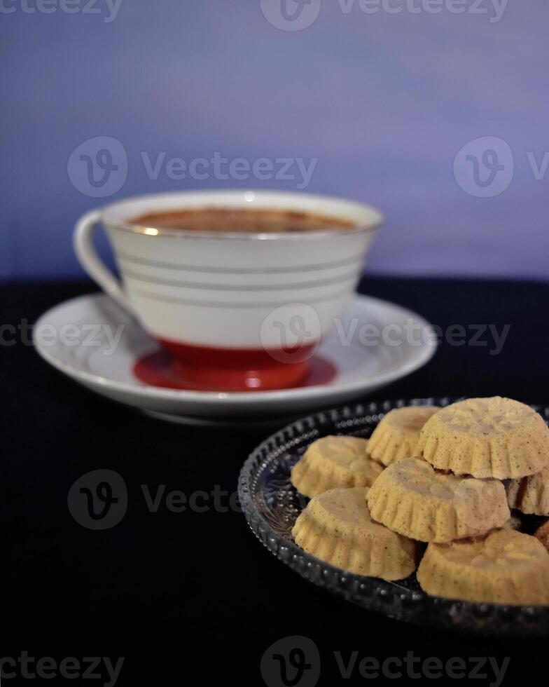 A cup of hot coffee and a plateful of kue satu or kue koya, a popular dry traditional cookie commonly found in Java, made of sweet mung bean powder that crumbles when bitten. photo