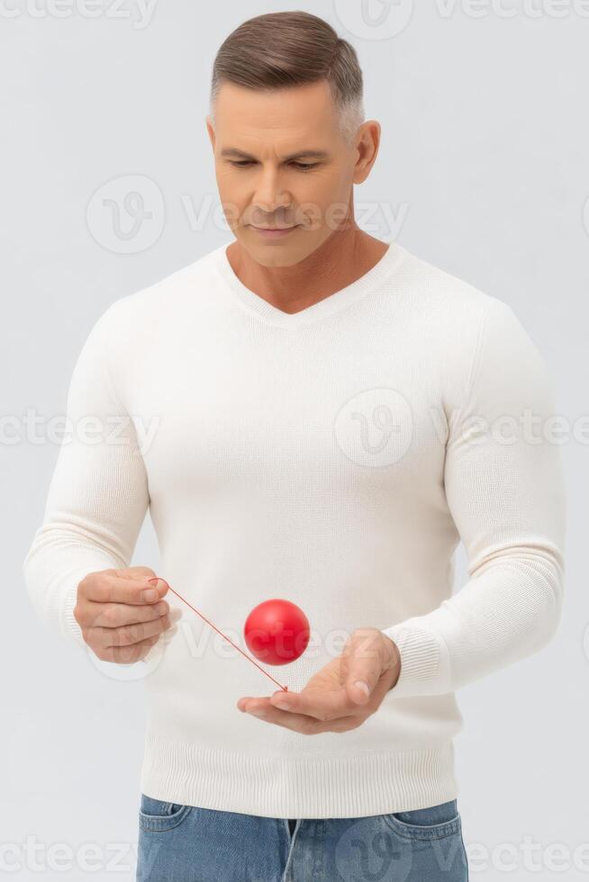 Focused Man Playing with Red Yo Yo Against Gray Background photo