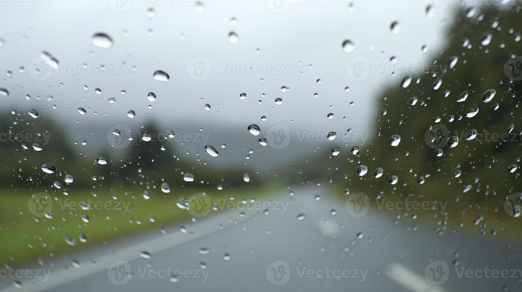 Rain Droplets On Windshield Blurring Road And Green Landscape photo