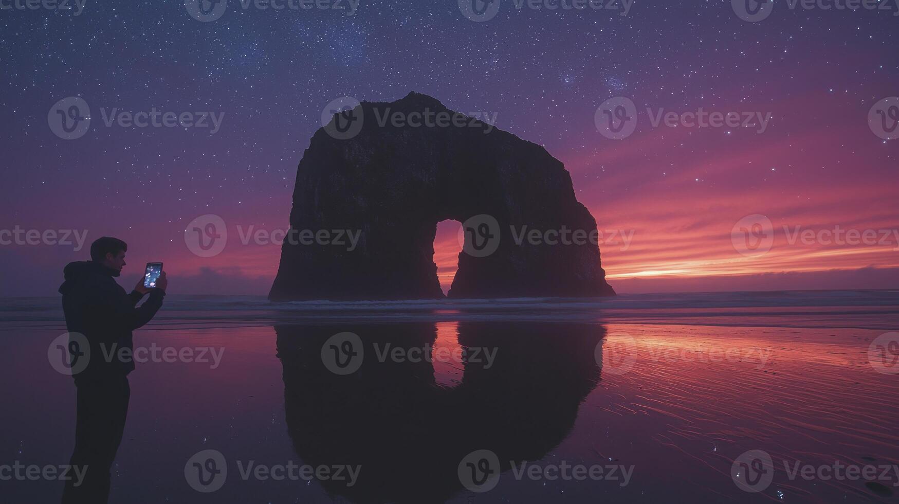 A man taking a photo of a rock formation at sunset