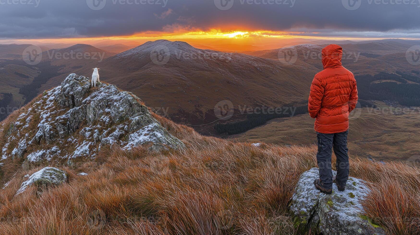 A person standing on a mountain top looking at the sunset photo