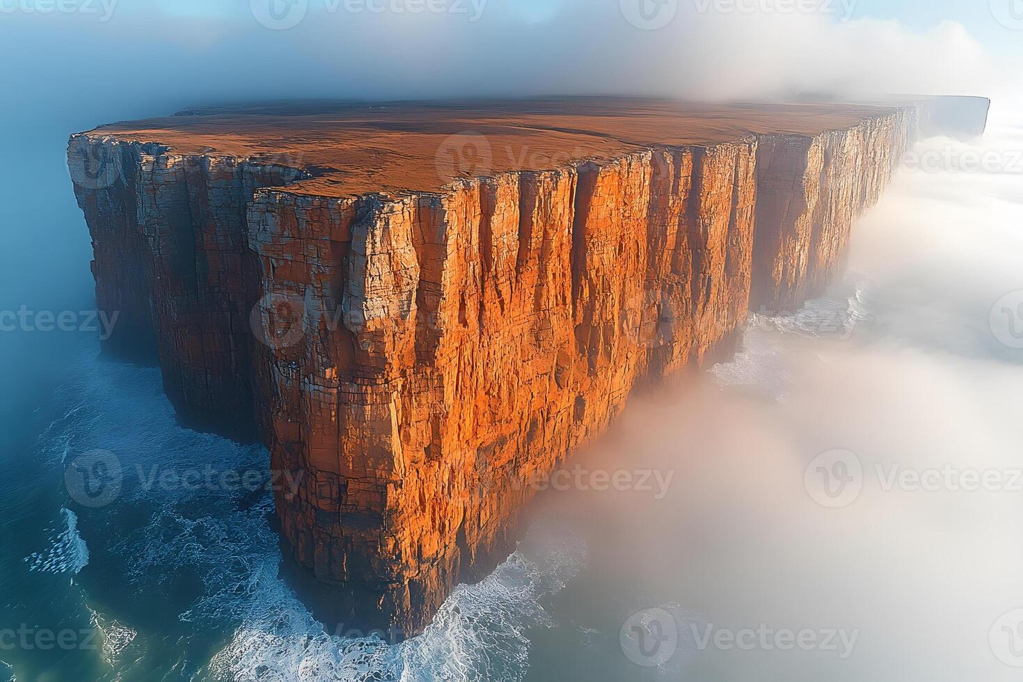 Majestic Aerial View of Rugged Cliffs Surrounded by Rolling Fog Over Ocean Waves photo
