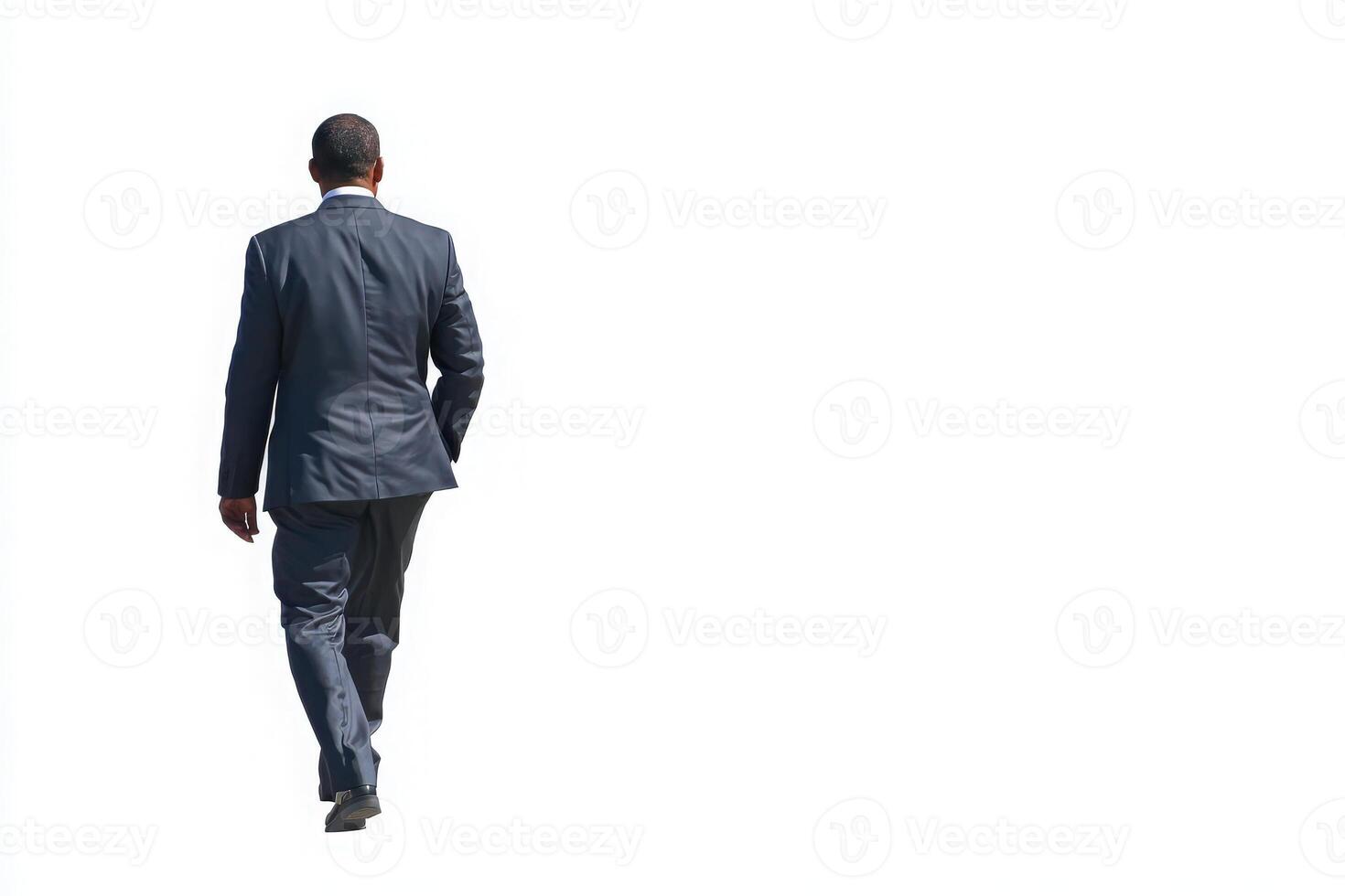 A man dressed in a dark suit is seen walking away. The bright background emphasizes his silhouette. He appears focused and determined, leaving a professional impression. photo