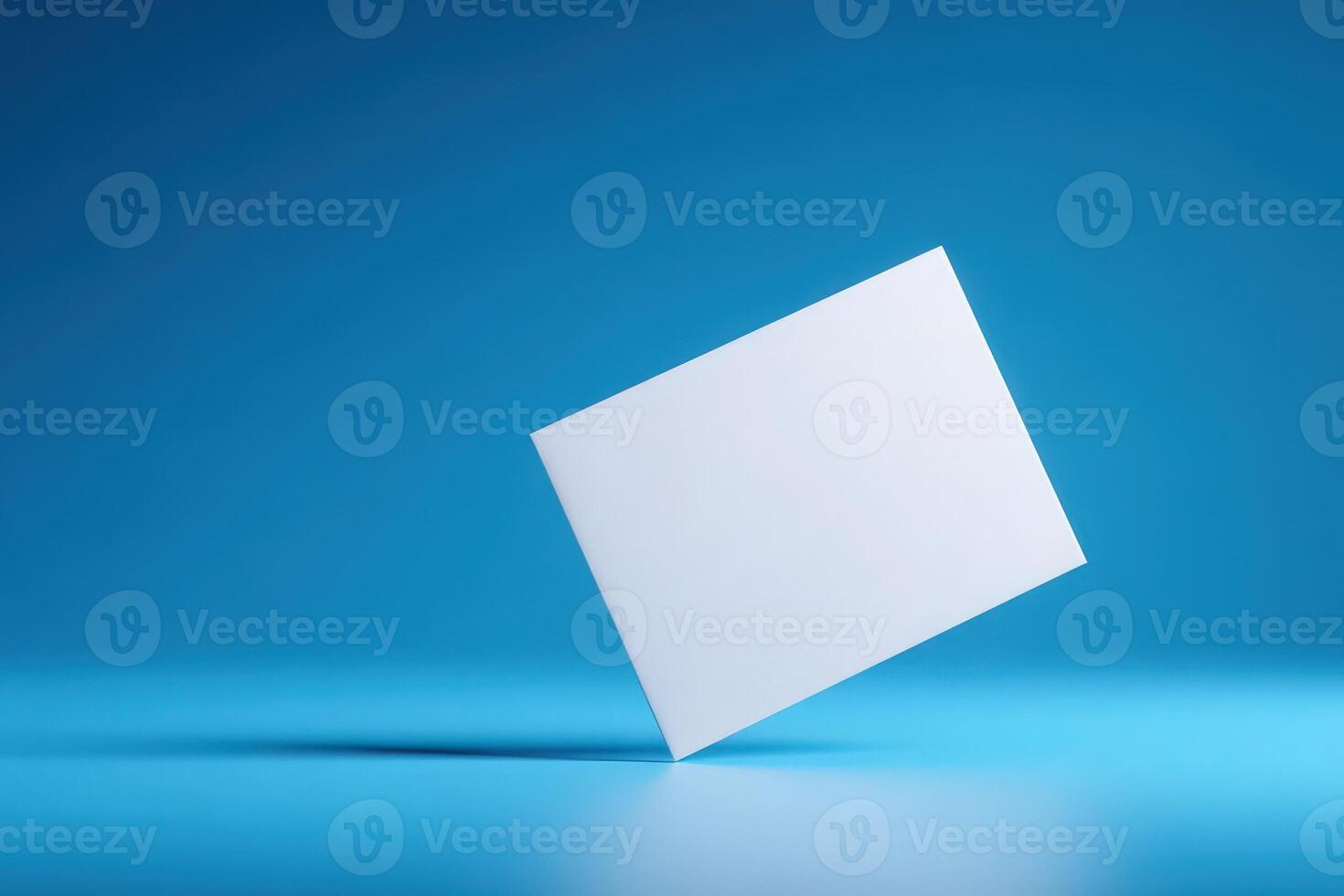A blank white card hovers above a smooth blue surface, showcasing its potential for various uses like invitations or branding. The vibrant blue adds a lively touch to the simple design. photo