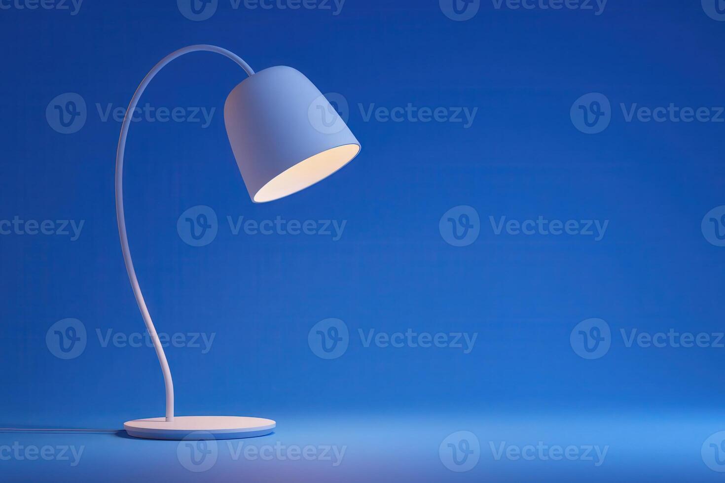 A stylish desk lamp stands on a smooth surface, casting a warm glow. The sleek design features a curved neck and a minimalist shade, creating a calming atmosphere in a blue-toned environment. photo