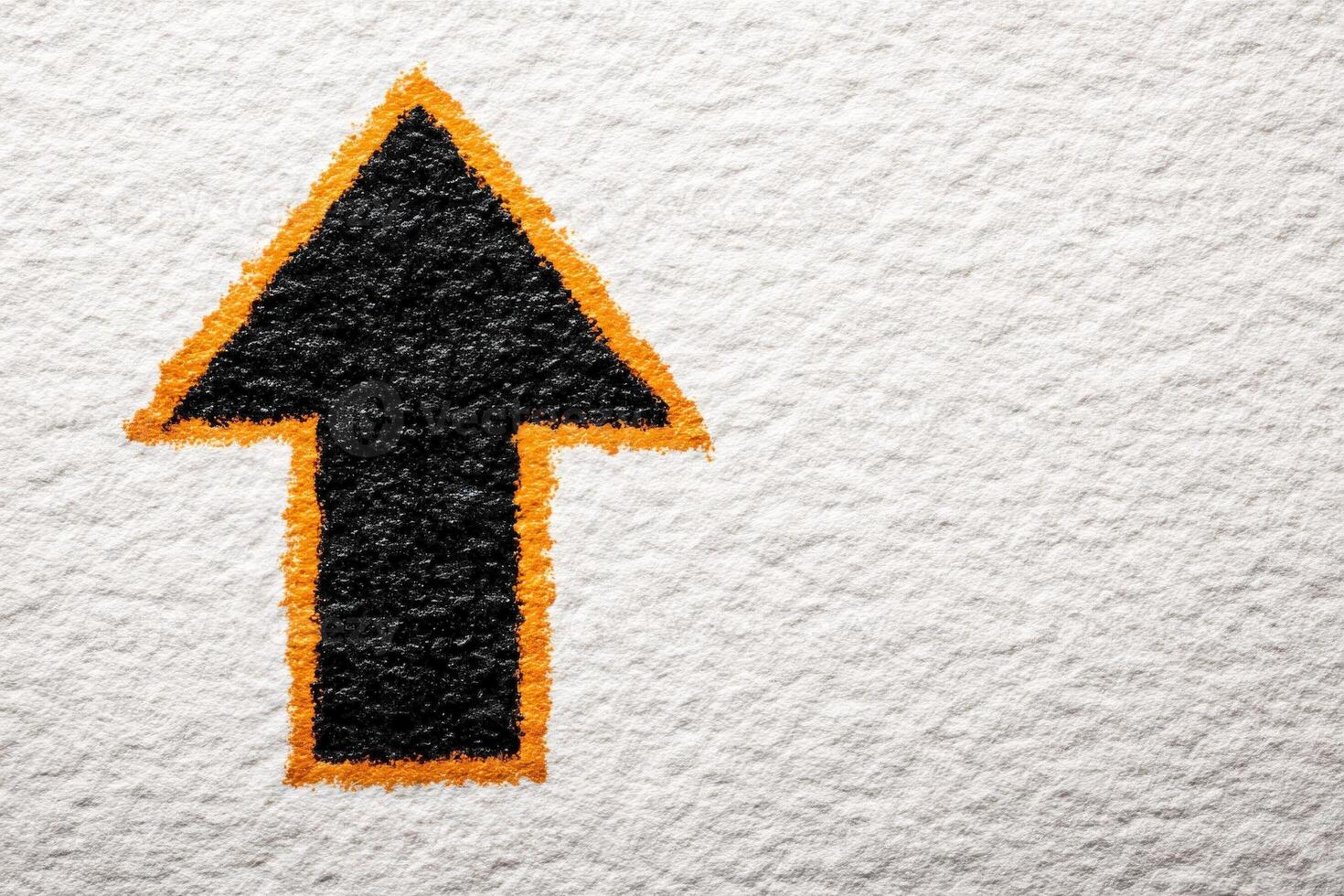 A black arrow symbol, outlined in orange, points upwards on a textured white background. The contrast between the dark arrow and the light surface creates a striking visual effect. photo