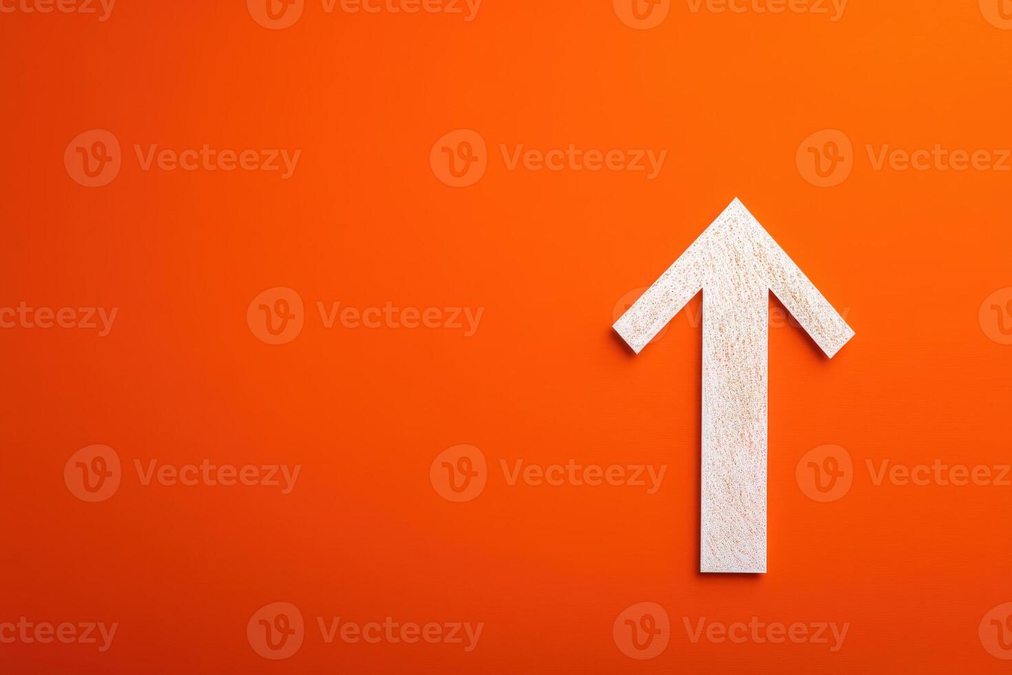 A white wooden arrow points upward prominently displayed on a bright orange background. The contrast creates an eye-catching focal point that conveys a sense of direction and positivity. photo