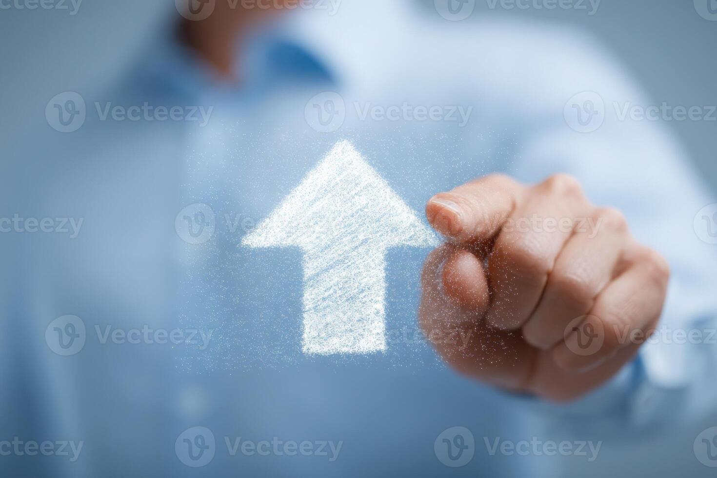 A person in a light blue shirt uses their finger to point at a chalk-like upward arrow. The background is blurred, suggesting a modern office environment, highlighting the theme of growth. photo