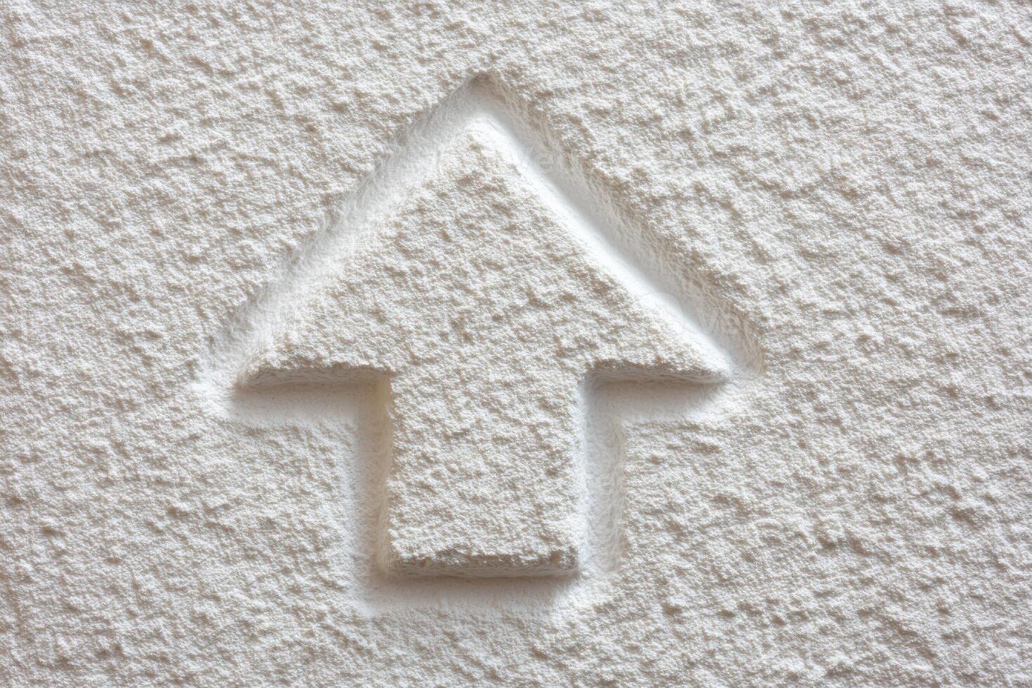 A close-up view of a textured white wall featuring a raised arrow shape. The design appears simple yet effective, implying direction or focus. photo