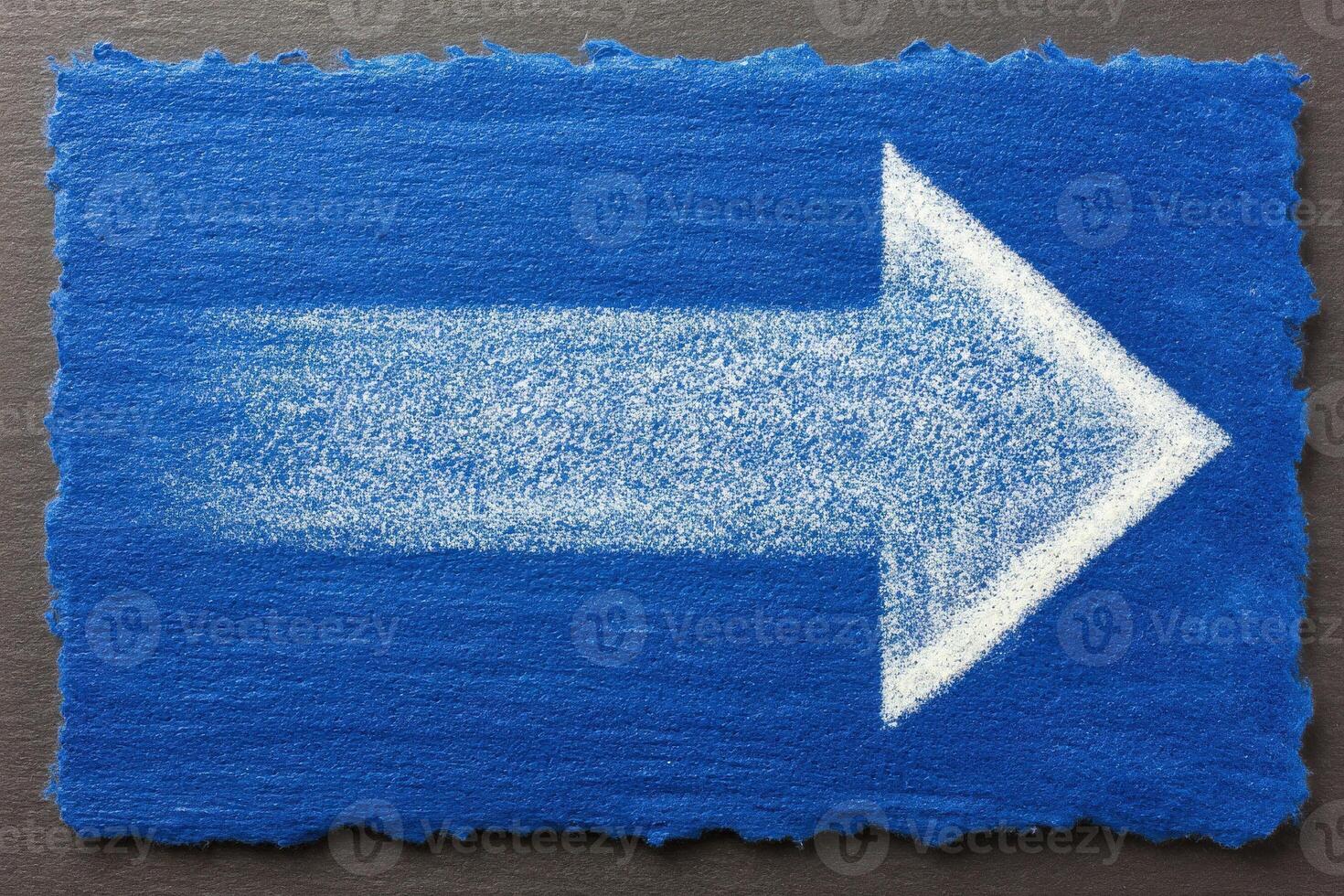 A vibrant blue rectangular surface features a large, white arrow on the right side, suggesting direction. The arrow appears drawn with a fine texture, enhancing visibility and clarity. photo