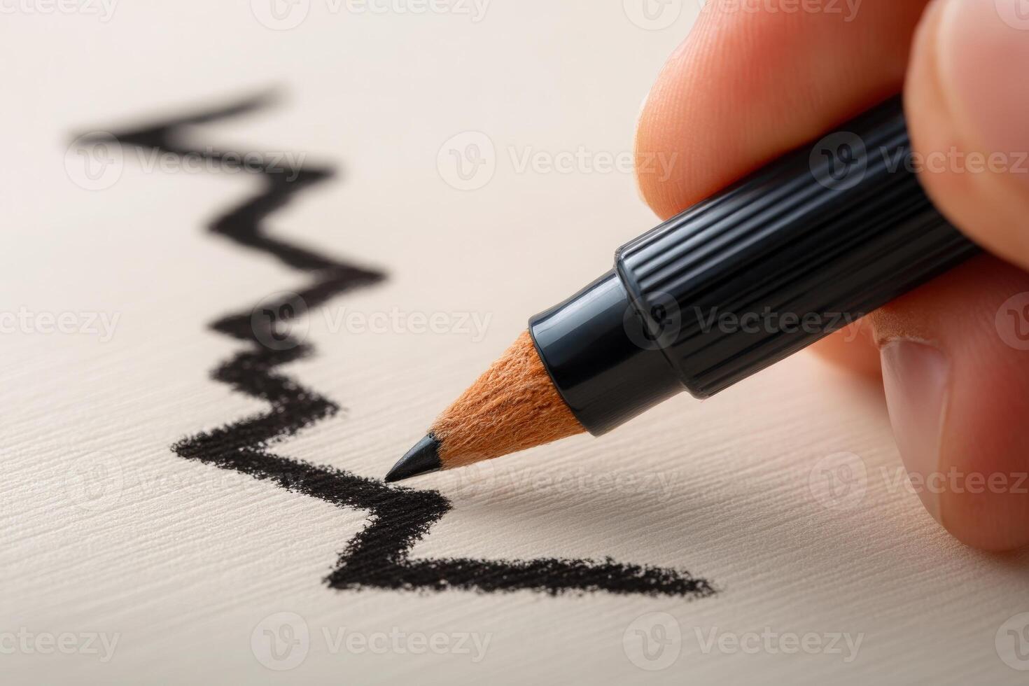 A hand holds a black marker, drawing a jagged line across a smooth, light-colored surface. The focus is on the interaction between the marker and the paper, capturing the moment of creativity. photo