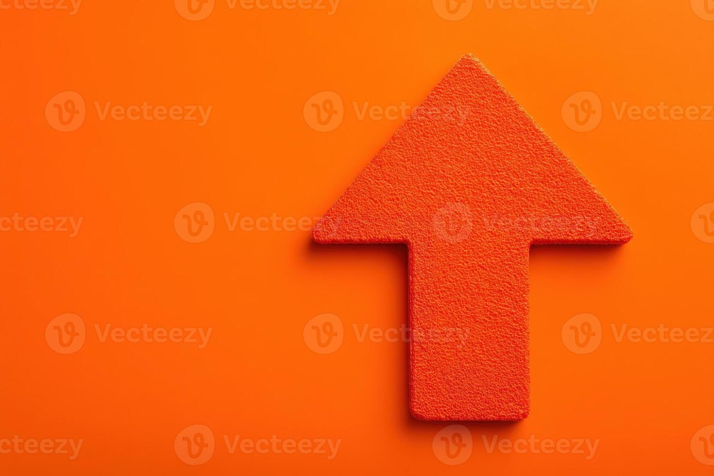 An upward-pointing arrow in a vivid orange color is set against a matching textured background, creating a bold and eye-catching visual element that suggests movement or progress. photo
