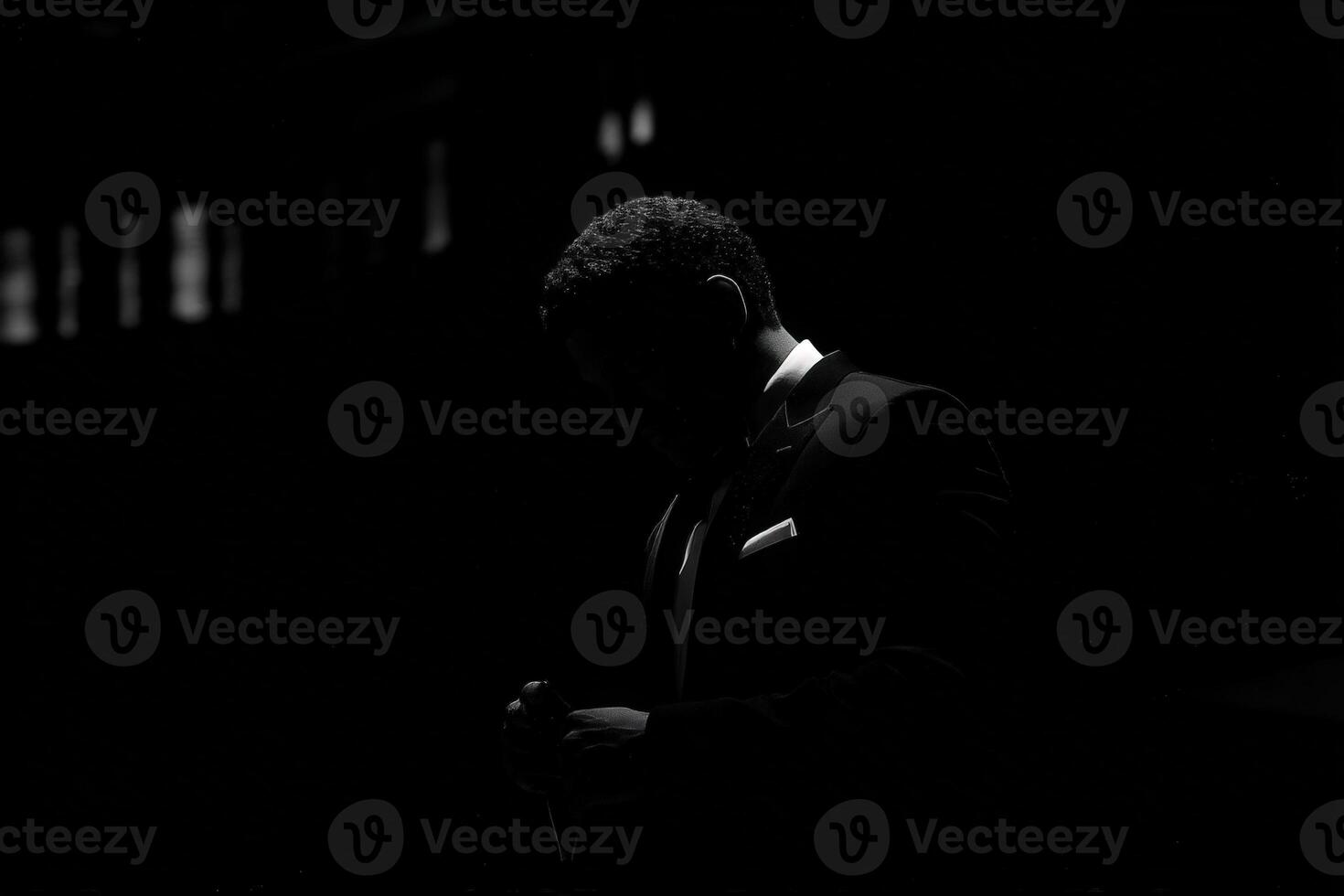 A well-dressed man in a suit is adjusting his cufflinks in a dimly lit environment, suggesting anticipation for an upcoming event. The focus is on his silhouette and refined attire. photo
