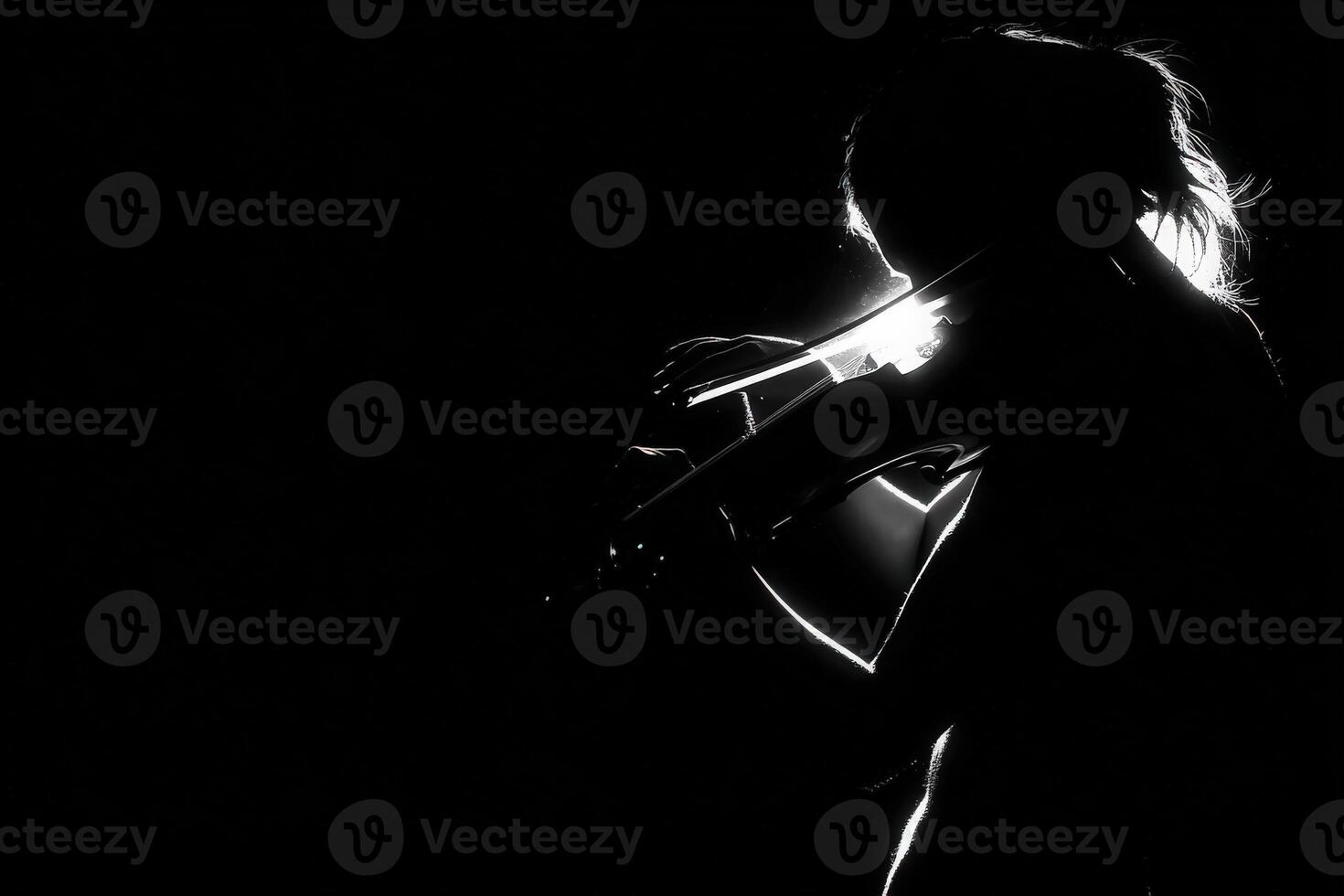 A violinist is captured in silhouette, playing passionately. Soft light highlights her figure as she becomes engrossed in her music, embodying artistry and emotion against a dark background. photo